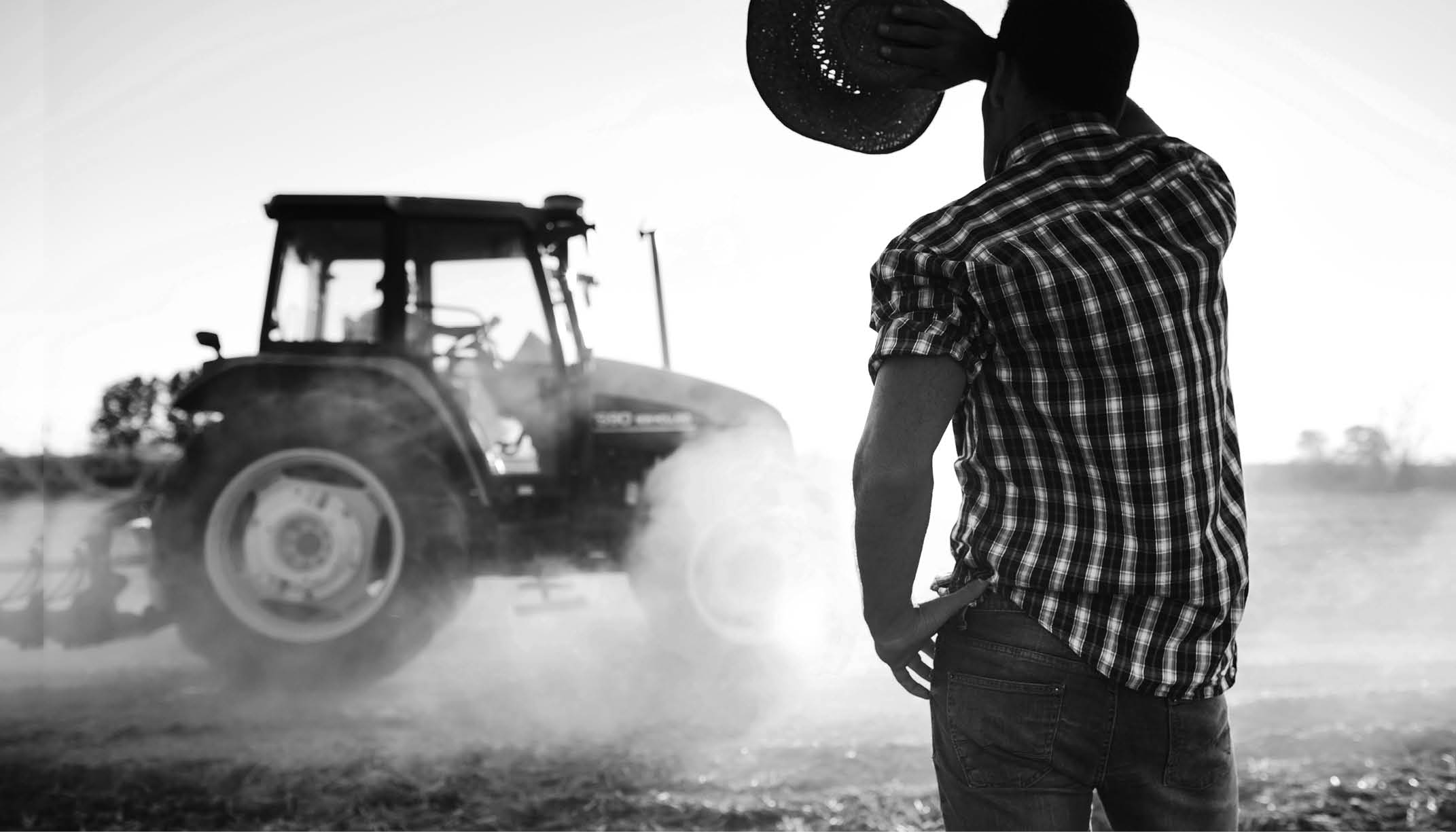 Farmer covers face from sun in a hot day at the fields as tractor passes by. More files of this series and models on port.