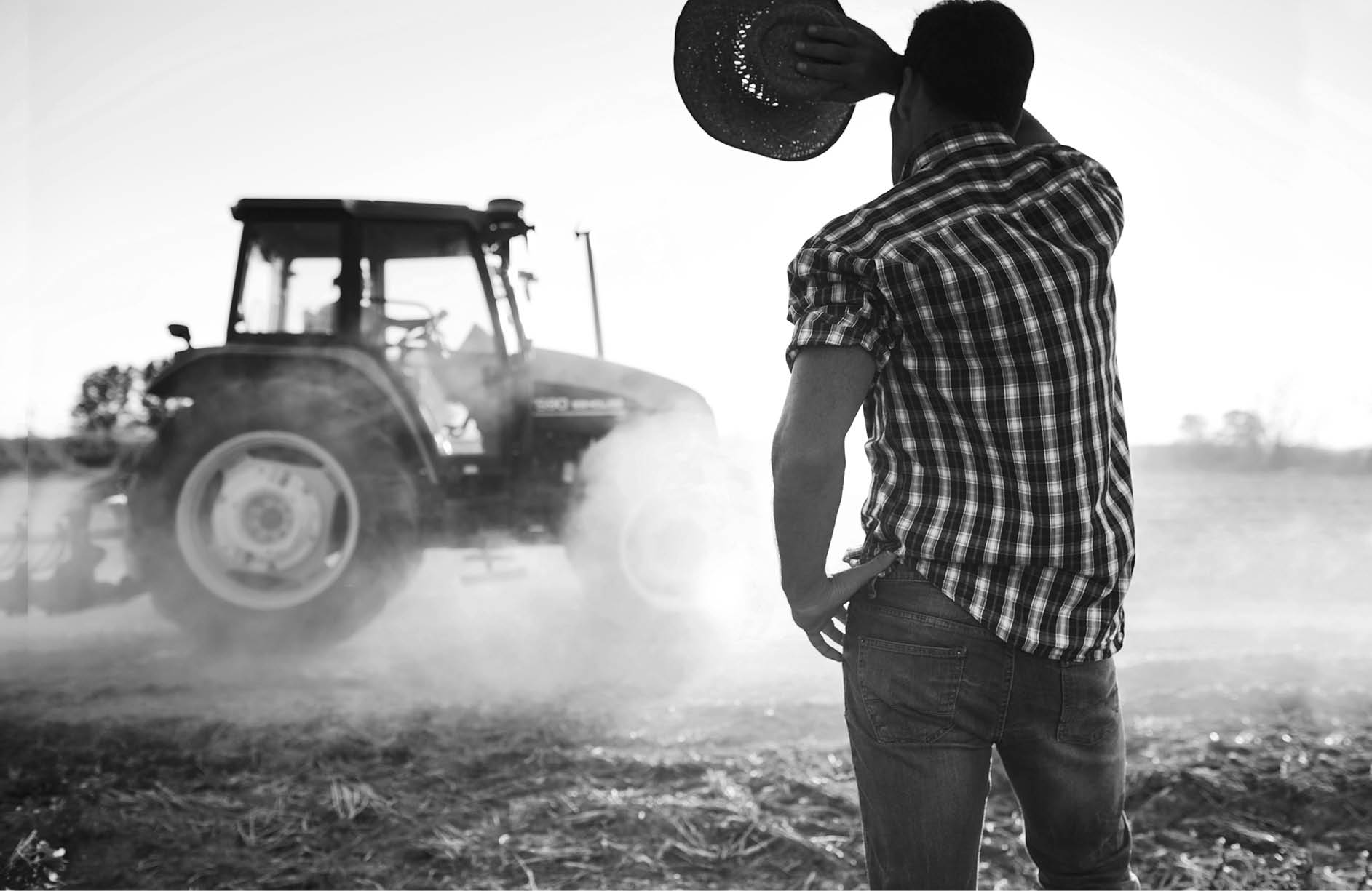 Farmer covers face from sun in a hot day at the fields as tractor passes by. More files of this series and models on port.