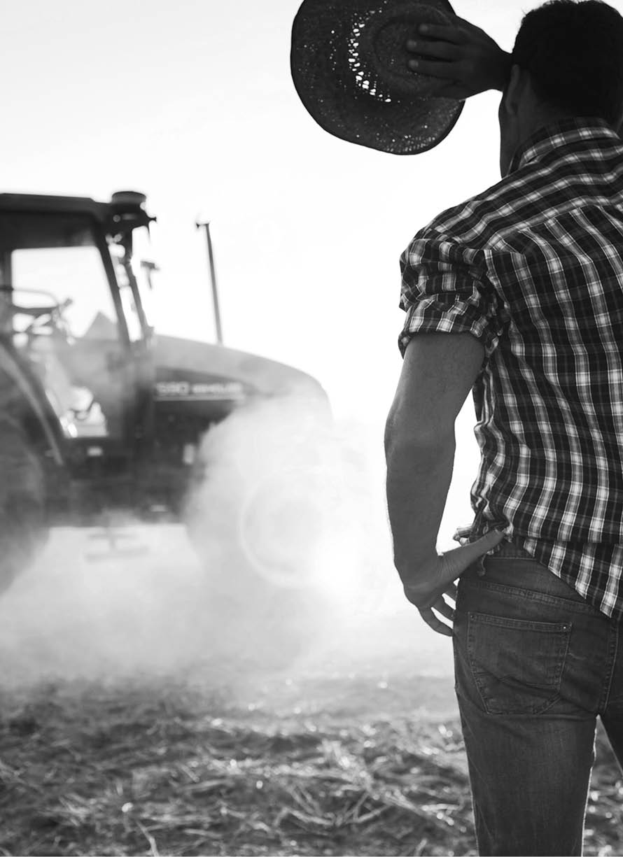 Farmer covers face from sun in a hot day at the fields as tractor passes by. More files of this series and models on port.